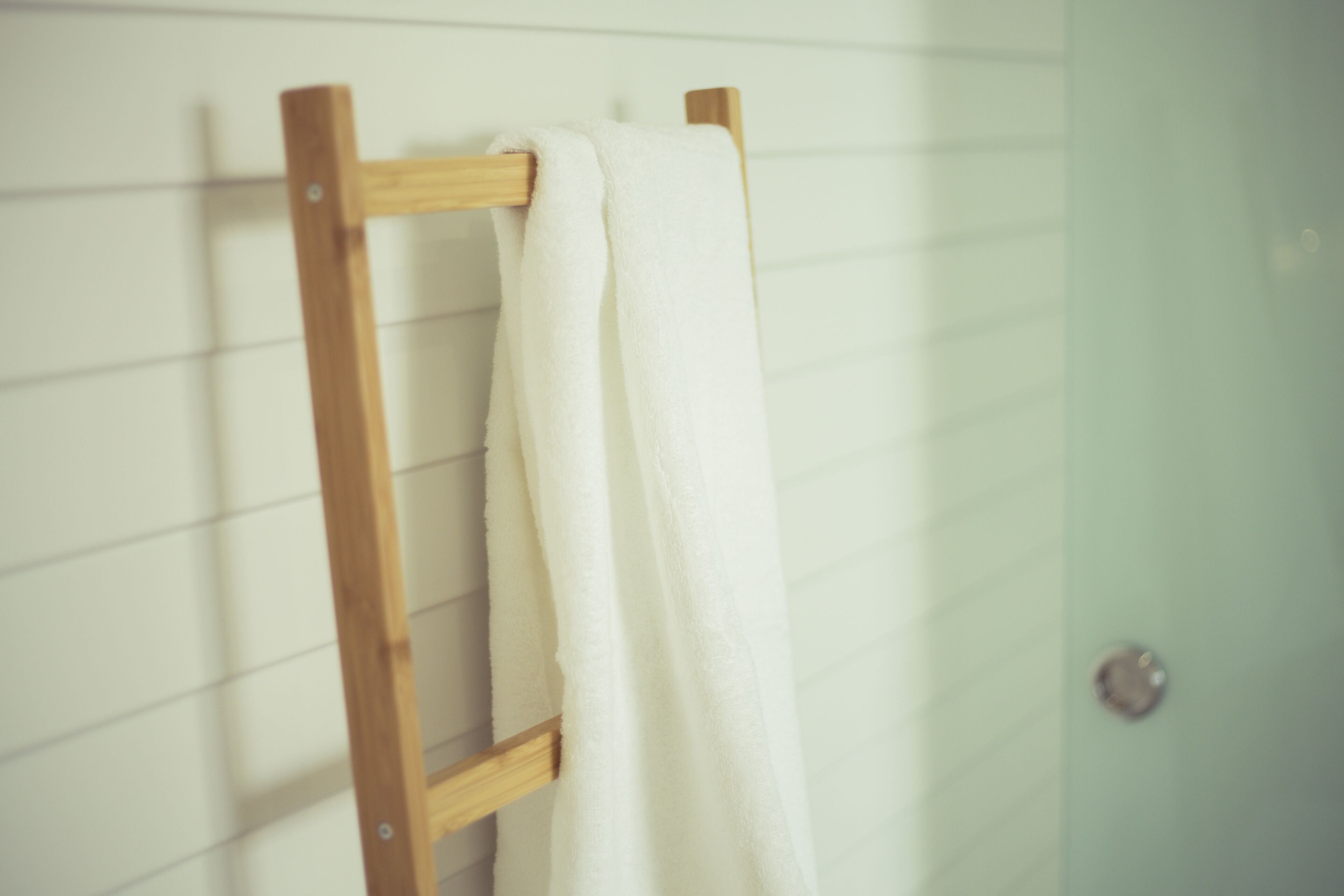 A wooden towel rack with a white towel hanging on it.