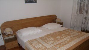 Un lit simple avec une tête de lit en bois, du linge de lit blanc et un plaid à motifs.