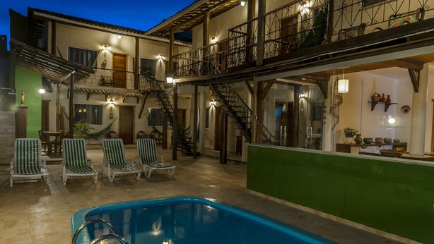 A pool area with lounge chairs and a staircase leading to an upper level. - Pousada Pé na Estrada (Porto Seguro)