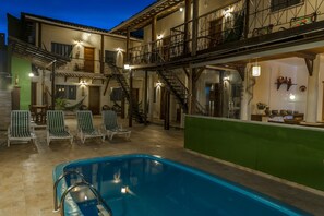 A pool area with lounge chairs and a staircase leading to an upper level.