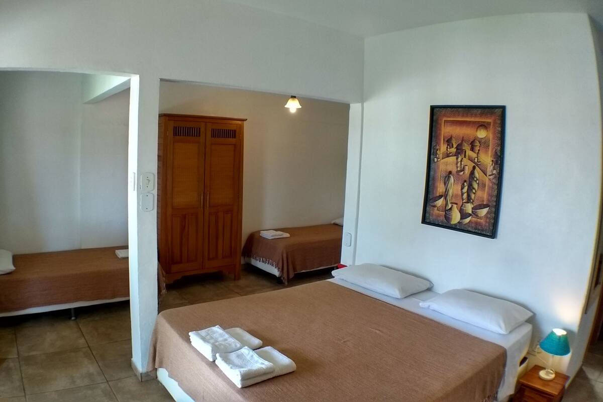 Ein Hotelzimmer mit zwei Einzelbetten, einem Holzschrank, einem Bild an der Wand und einem kleinen Tisch mit Lampe.