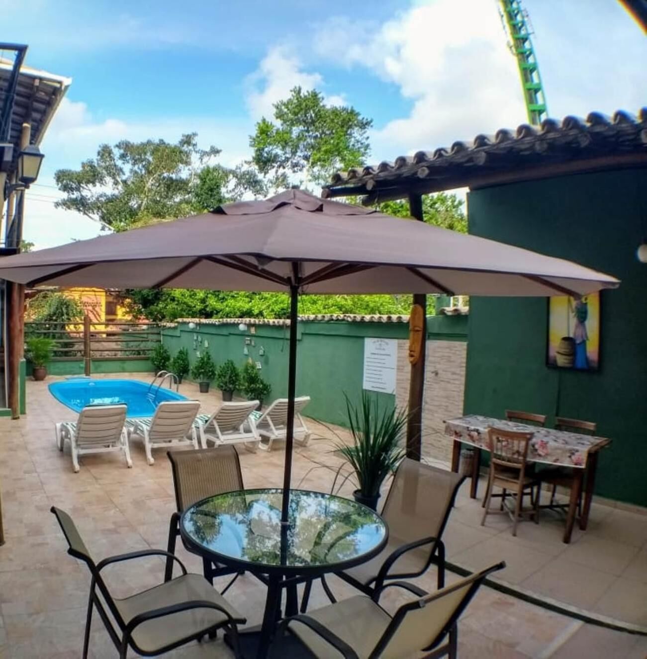 An outdoor patio with a pool, lounge chairs, and a table with chairs.