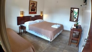 A hotel room with a bed, a ceiling fan, a bedside table, a small table with a lamp, and a mirror on the wall. - Pousada Pé na Estrada (Porto Seguro)