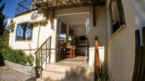 A house with a staircase leading to a dining area, a TV mounted on the wall, and a balcony with a railing. - Pousada Pé na Estrada (Porto Seguro)