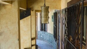 Ein Korridor mit Steinwand, Metallgittern und einer Pendelleuchte.