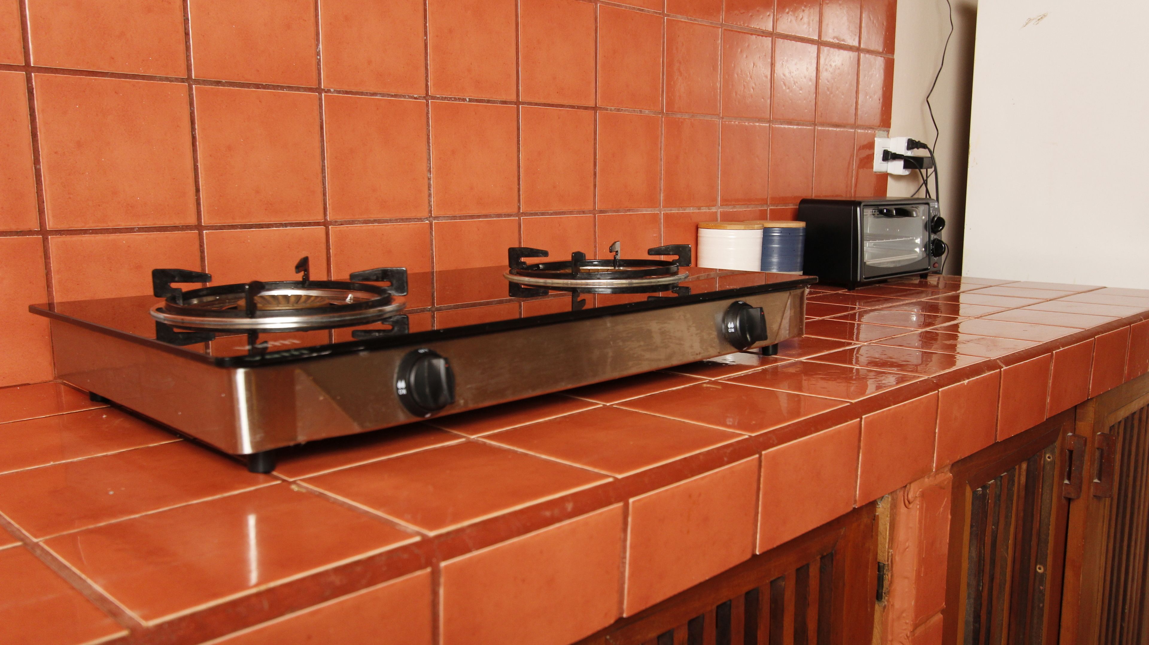 A kitchen with a gas stove, a toaster, and a water dispenser on the countertop.