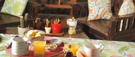 Une table de petit-déjeuner avec divers aliments, une cafetière et un verre de jus de fruits.