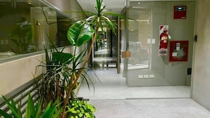 A hallway with potted plants, a fire extinguisher, and a door leading to another room. - Rent 2888 (Buenos Aires)