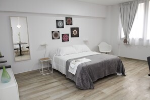 A modern bedroom with a bed, bedside tables, a mirror, artwork on the wall, and a window with curtains. - Rent 2888 (Buenos Aires)