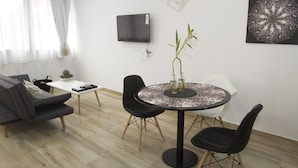 A modern living room with a sofa, a dining table with chairs, a flat-screen TV mounted on the wall, and a decorative plant. - Rent 2888 (Buenos Aires)