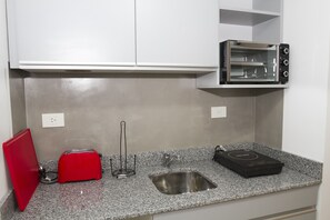 A kitchen with a granite countertop, a toaster, a kettle, and a small oven. - Rent 2888 (Buenos Aires)