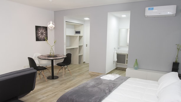 A modern hotel room with a bed, a desk, chairs, and a bathroom. - Rent 2888 (Buenos Aires)