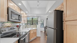 A modern kitchen with wooden cabinets, stainless steel appliances, and a tiled backsplash. - Rare 3 Bedrm 2 Bath corner unit with unobstructed Spectacular Mountain Views (Tucson)