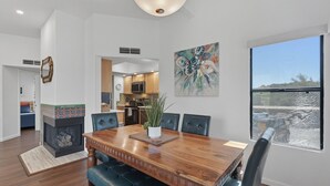 A dining area with a wooden table, black upholstered chairs, a potted plant, and a large window with a view. - Rare 3 Bedrm 2 Bath corner unit with unobstructed Spectacular Mountain Views (Tucson)