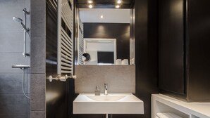 Een moderne badkamer met een wit wastafel, een spiegel en een douche.