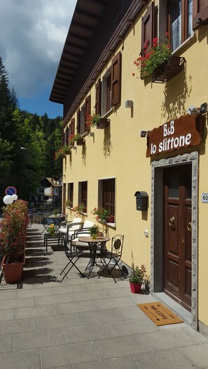 Un edificio con un letrero que dice "B&B lo slittone" y asientos exteriores con mesas y sillas.