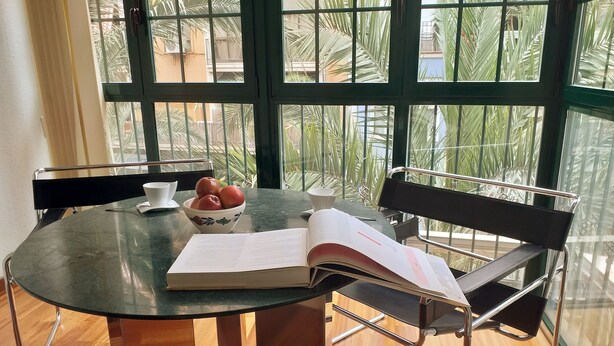 A round table with a bowl of apples, a book, and a cup. - COLLECTION Bed & Breakfast, Centro Alicante I Cocina & Terraza - Jardín  (Alicante)