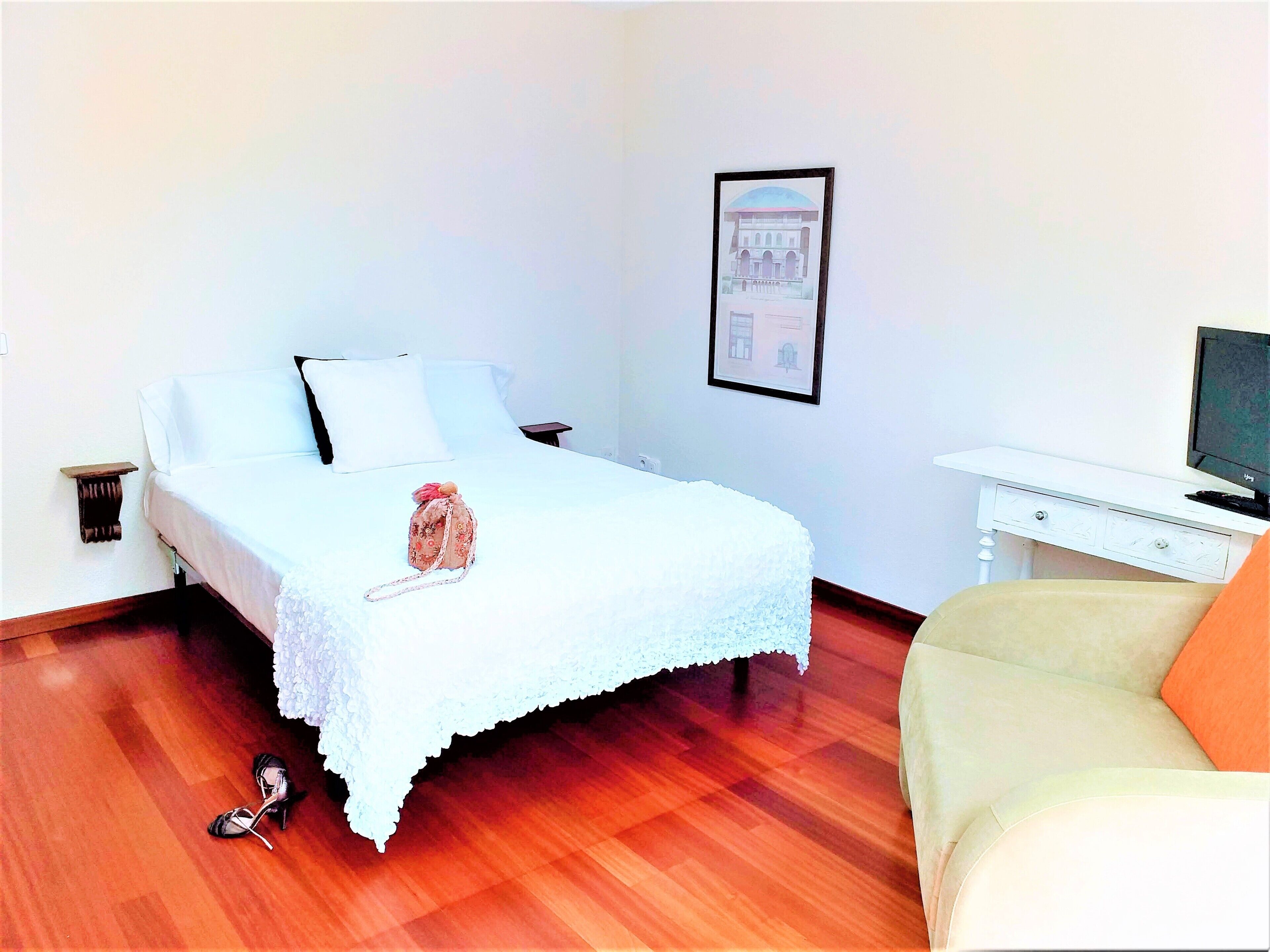 Una habitación de hotel con una cama, una mesita, un televisor y una silla.