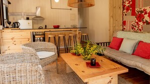 Et hyggeligt rum med fletmøbler, et træbord med en vase og en sofa med røde puder.