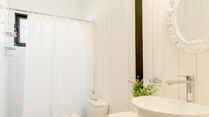 Et badeværelse med hvid vask, toilet og bruseforhæng.