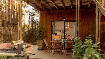 A wooden deck with a dining area, a fire pit, and a view of the kitchen through a glass door.