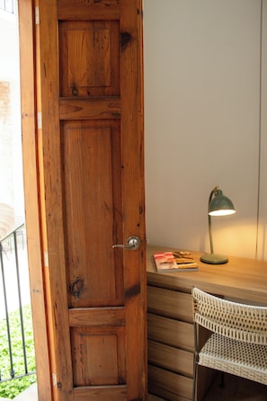 Una puerta de madera, un escritorio con una lámpara y una silla de mimbre.