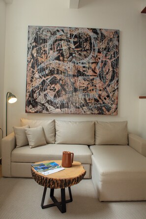 A living room with a large abstract painting, a sofa, a coffee table, and a floor lamp.