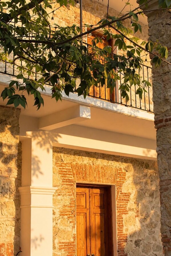 Un bâtiment doté d’une porte en bois, de murs en pierre et d’un balcon orné de rampes en métal.