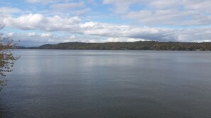 Un lago tranquilo con una orilla boscosa y un cielo parcialmente nublado.