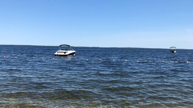 Un bateau sur une étendue d’eau calme, avec une eau claire et peu profonde près du rivage.