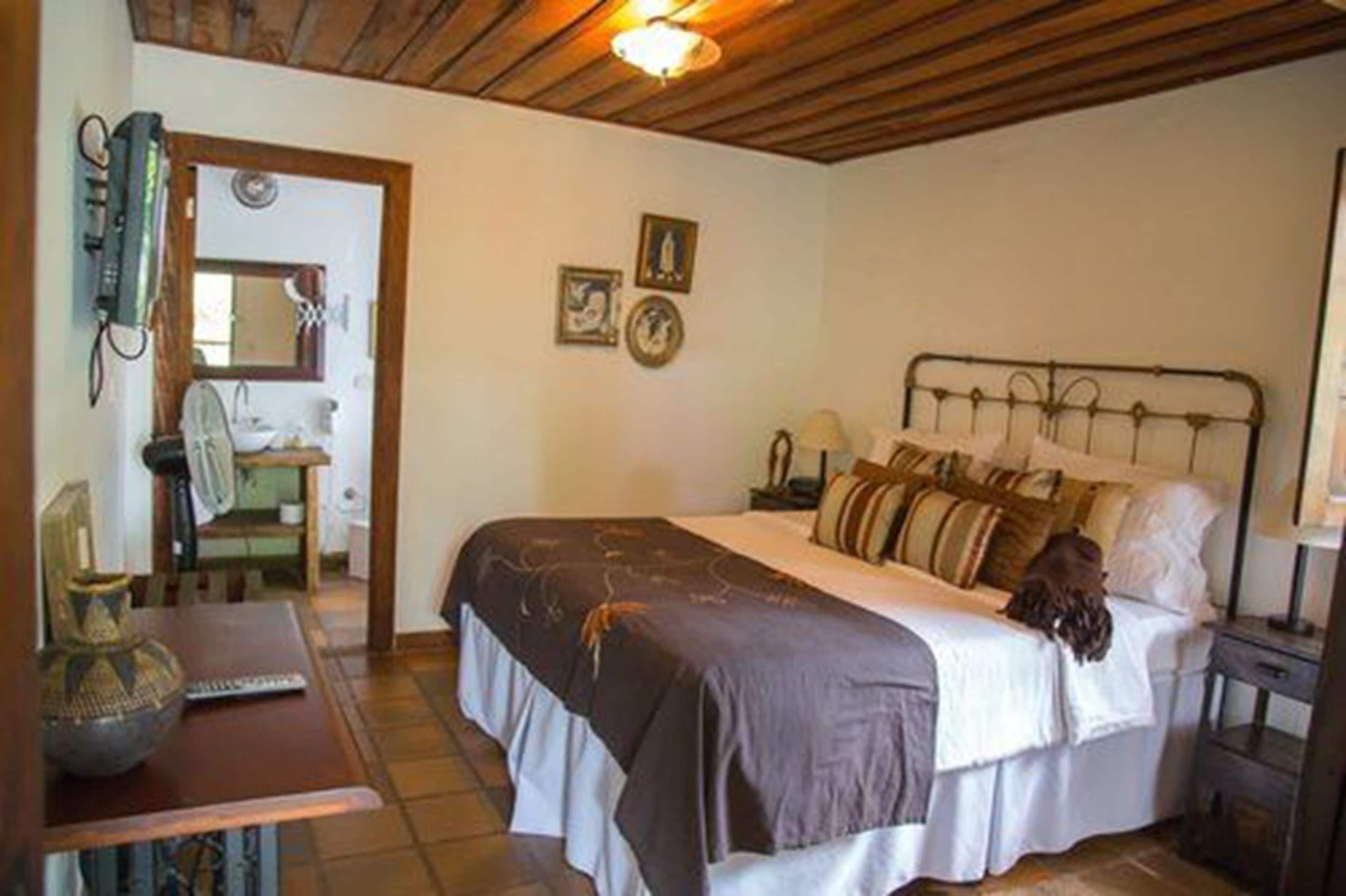 A bedroom with a bed, bedside table, lamp, and a wall-mounted heater.