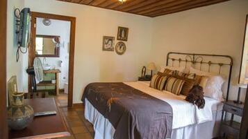 A bedroom with a bed, bedside table, lamp, and a wall-mounted heater.