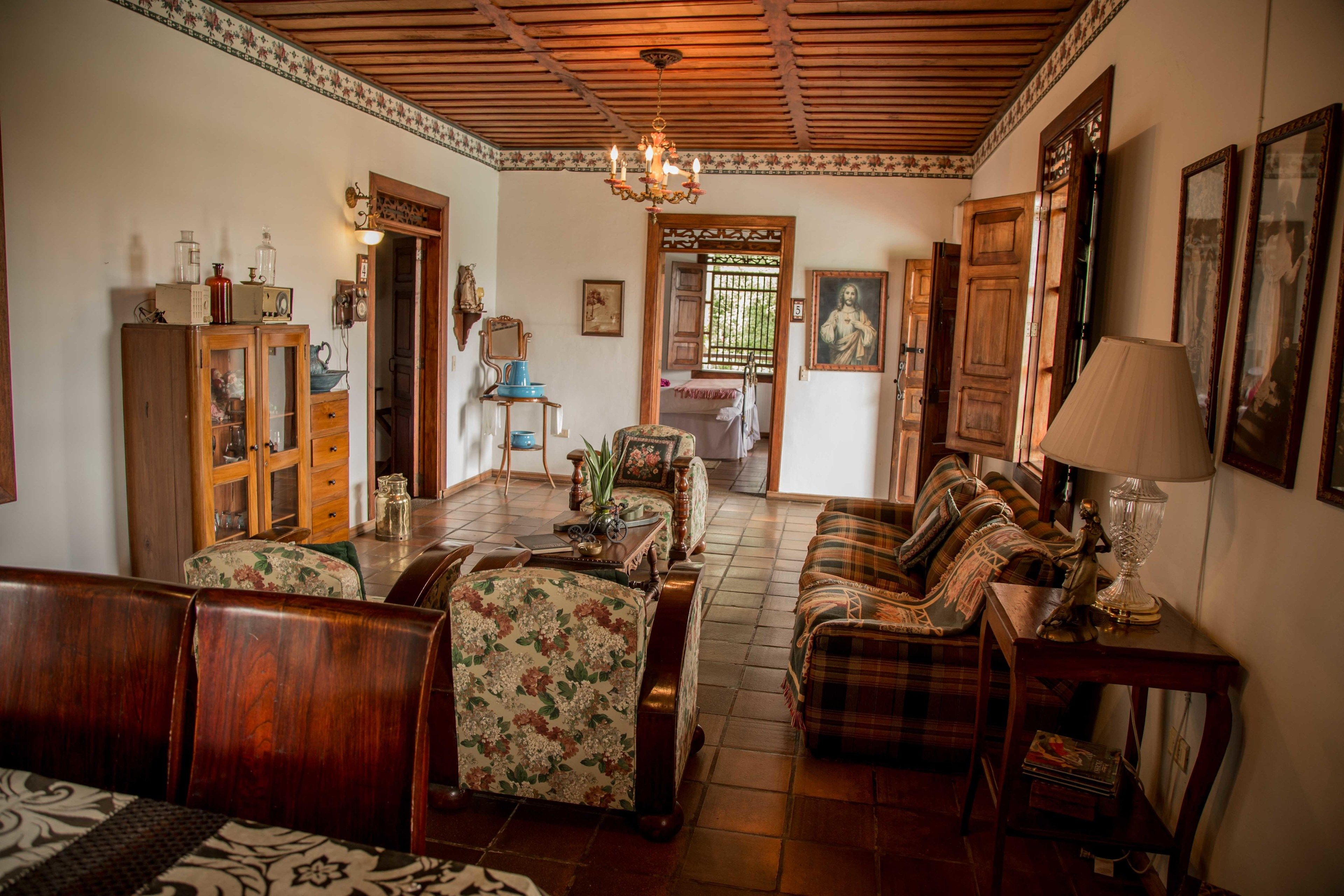 Un salón tradicional con muebles de madera, una araña y una zona de comedor con un aparador y una mesa.