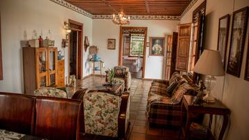 Un salón tradicional con muebles de madera, una araña y una zona de comedor con un aparador y una mesa.