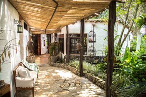 A covered outdoor area with stone flooring, a bench, and various plants. - Hotel Delirio Campestre (Montenegro)