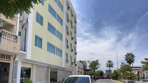 Un edificio de varios pisos con fachada plana, unidades de aire acondicionado y una entrada visible.