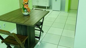Una cocina moderna con armarios blancos, una mesa de comedor de madera y un refrigerador pequeño.
