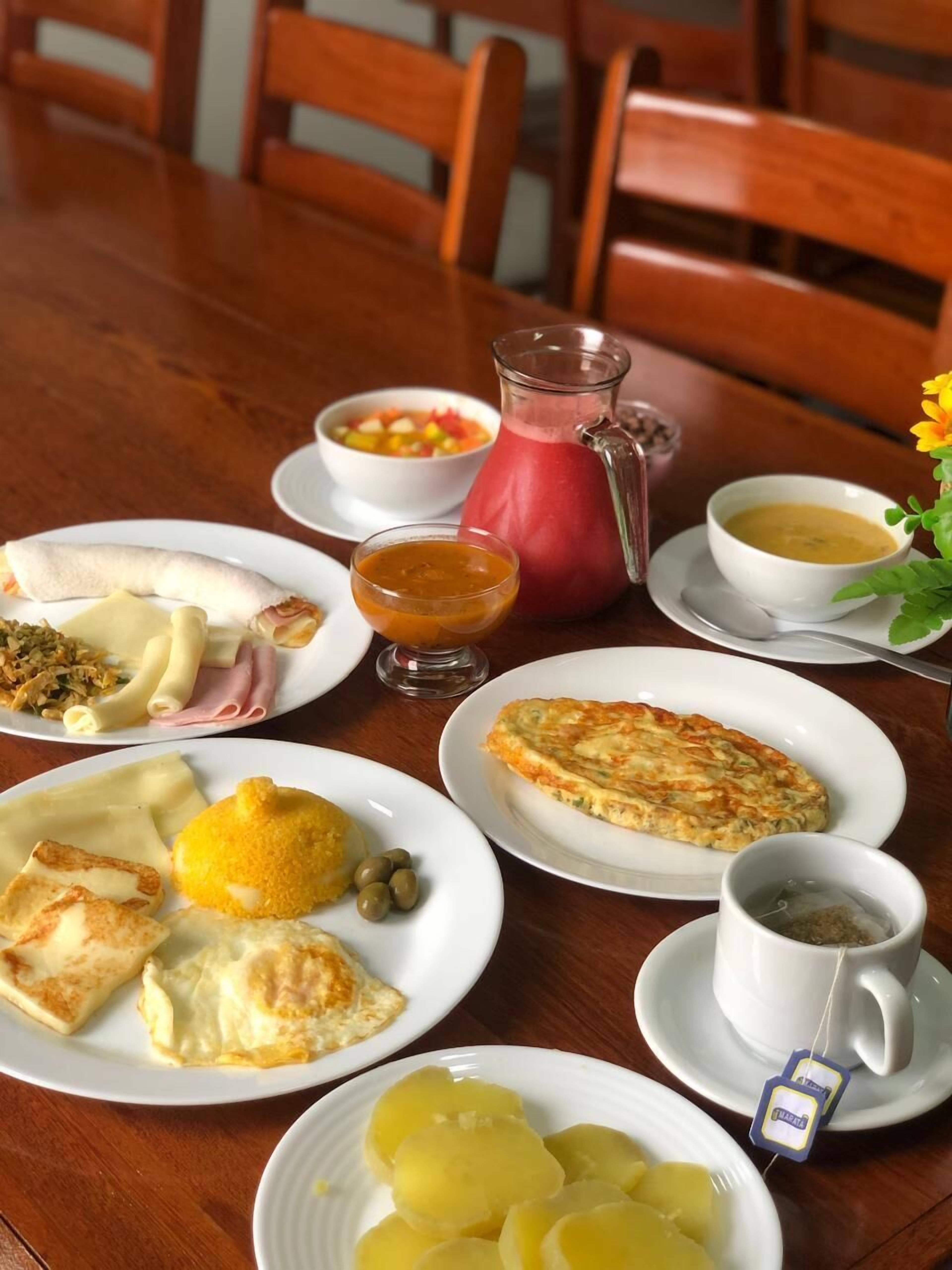 A breakfast table with plates of food, a pitcher, and a cup of tea.