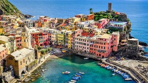 A coastal town with colorful buildings, a historic tower, and a clear view of the sea.