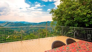 A balcony with a view of green hills and a clear sky.