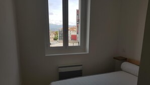 A bedroom with a bed, a window, and a radiator.