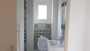 A compact bathroom with a toilet, a sink, and a window.