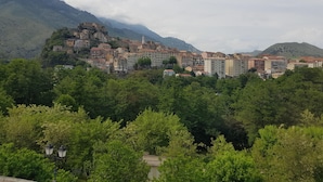 A hillside town with buildings nestled among trees, featuring a prominent church with a bell tower.