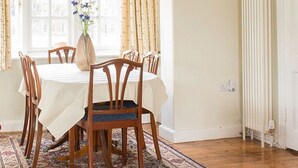 A dining area with a round table, six wooden chairs, and a patterned rug.