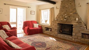 A living room with a stone fireplace, red sofas, and a patterned rug.