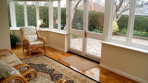 A sunroom with wicker furniture, large windows, and a view of the garden.