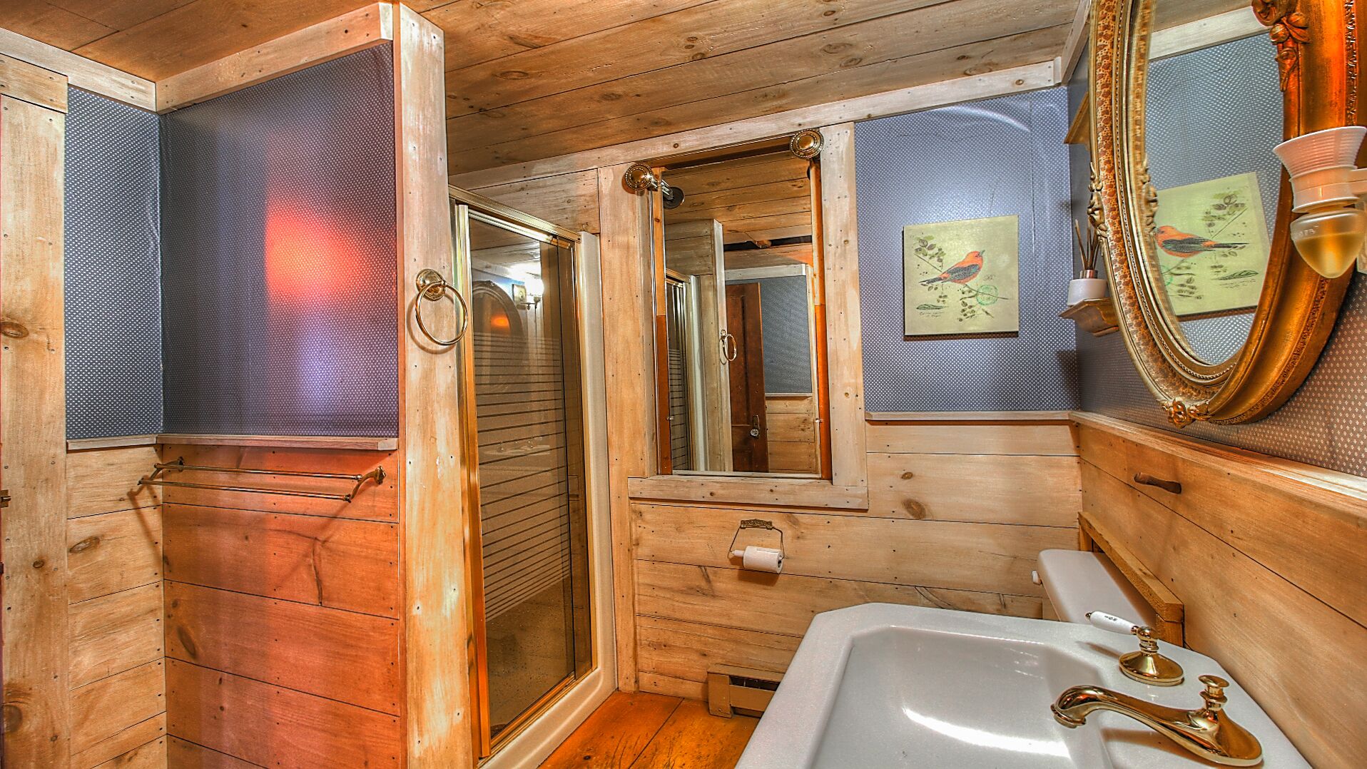 A wooden cabin bathroom with a shower, a sink, and a mirror.