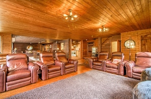 Een houten interieur met leren loungestoelen, een ronde spiegel en een kroonluchter.