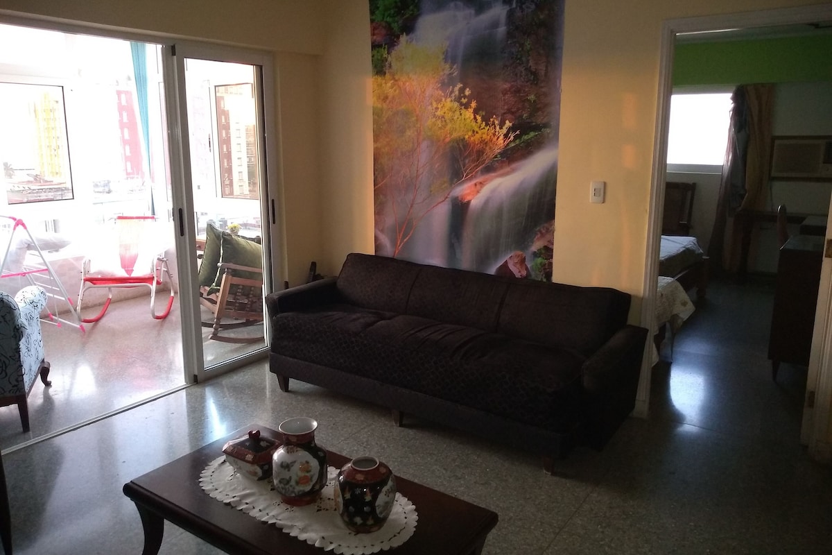 A living room with a sofa, a coffee table with decorative items, and a large painting of a waterfall.
