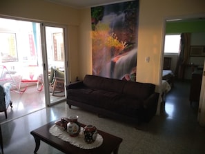 A living room with a sofa, a coffee table with decorative items, and a large painting of a waterfall. - Casa Issi Nelson (Havana)